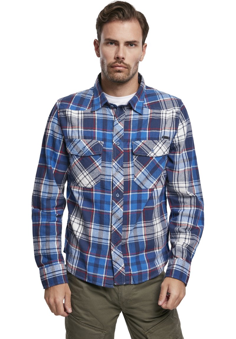 Camisa de franela de botones en patrón de cuadros azul y blanco con acentos rojos. Presenta dos bolsillos frontales y un cuello puntiagudo.