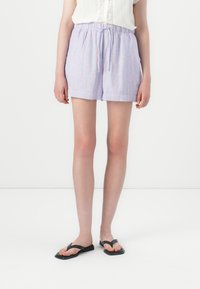 Lyseblå shorts med røde lodrette striber, elastisk talje og snor. Sammen med sorte flip-flops, flad design.