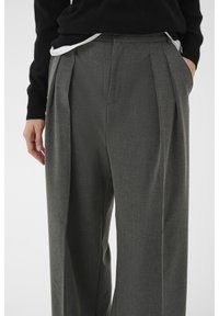 Hallid ülikonnapüksid, millel on sile tekstuur, esipleekide, küljetaskute ja kõrge vöökohaga disain.