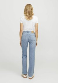 Traperice visokog struka u plavoj boji, s ravnim nogavicama, stražnjim džepovima i smešnom kožnom oznakom na struku.