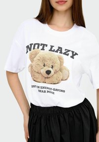 White cotton t-shirt featuring a soft teddy bear graphic and text "NOT LAZY" and "JUST IN ENERGY-SAVING BEAR MODE" in bold black letters.