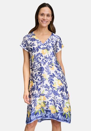 Kurzarmkleid mit V-Ausschnitt aus leichtem Stoff, das ein florales Zitronenmuster in Blau, Gelb und Grün mit einem kontrastierenden Saum zeigt.