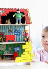 Puinen nukketalo punaisella katolla, värikkäällä kuviollisella sisustuksella, hahmot leikkisissä asennoissa ja keltaiset portaat johtavat toiseen kerrokseen.