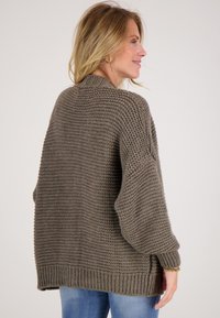 Overmaatse gebreide trui in olijfgroen, met een textuurpatroon, geribbelde zoom en taps toelopende mouwen voor extra comfort.