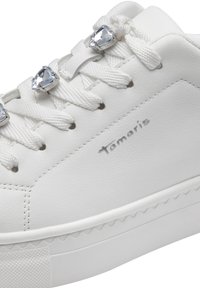 Sneaker bianco realizzato in morbida pelle sintetica, con lacci piatti, tre gemme decorative sulla linguetta e una suola in gomma texture.