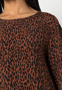 Leopardenmuster-Top in Braun und Schwarz, mit einem weiten, runden Ausschnitt und einem weichen Stoff mit glatter Textur.