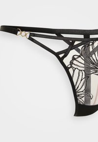 Schwarzer Spitzen-Tanga mit besticktem Blumenmotiv, transparentem Stoff in hautfarbigen Akzenten, verstellbaren Trägern und Hardware in goldfarbener Farbe.
