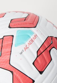 Pallone Nike Academy con una superficie bianca liscia, caratterizzato da motivi geometrici rossi e turchesi, design cucito e dettagli del marchio.