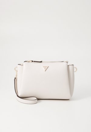 Biała teksturowana skórzana torba na ramię z złotym zamkiem błyskawicznym, trójkątnym logo Guess oraz odpinanym paskiem na jednolitym tle.