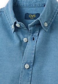 Camicia azzurra chiara con colletto strutturato, tessuto testurizzato, bottoni bianchi e un'etichetta con la scritta "OVS kids."