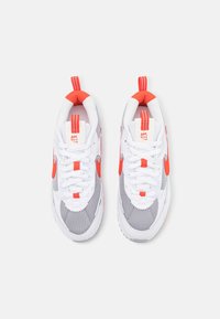 Nike-sneakers med en vit och grå mesh-överkonstruktion, ljusa orange detaljer, tjocka snören och en strukturerad sula med vadderad krage.