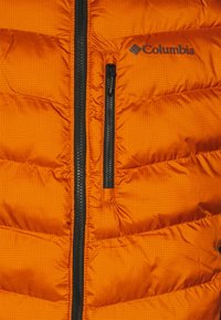 Jasně oranžová nadýchaná bunda s vodorovným prošíváním a černou kapsou na zip, se znakem Columbia na pravém horním rohu.