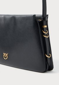 Sacola de ombro de couro preta com um design elegante, apresentando um detalhe em metal dourado e três argolas de um lado para ajuste do comprimento da alça.