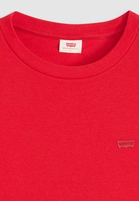 T-shirt rouge à rayures côtelées à manches courtes en coton, avec un col rond et un petit logo Levi's en relief sur le bas à l'avant.