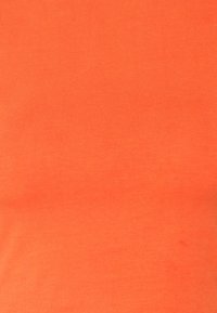 T-shirt en coton, couleur orange vif, texture lisse, coupe ajustée, design minimaliste sans motifs ni détails métalliques notables.