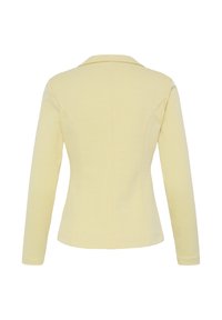 Vue arrière d'un blazer jaune pâle ajusté avec manches longues et col, présenté sur un fond blanc.