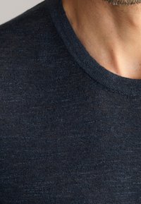 Ciemnoniebieska koszulka krótki rękaw z okrągłym dekoltem, wykonana z teksturowanej tkaniny z subtelnymi wariacjami kolorystycznymi.