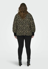 Juodai ir beige spalvų leopardų rašto megztinis, su laisvu kirpimu ir burbulinėmis rankovėmis. Derinamas su juodomis kelnėmis ir aukštakulniais batais.