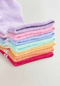 Rôzne bavlnené ponožky usporiadané v gradácii farieb: fialová, ružová, svetlomodrá, mäta zelená, žltá, oranžová a červená. Každá má jemnú textúru.