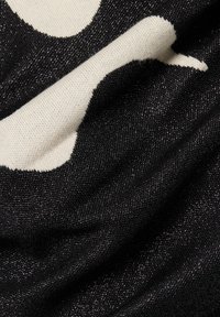 Tissu tissé noir et crème avec un motif en chevrons, présentant une texture brillante et un design graphique distinctif aux couleurs contrastées.