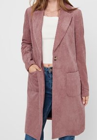 Cord-Mantel in verstaubtem Rosaton, mit aufgeschlagenem Kragen, zwei Vorderentaschen, Ein-Knopf-Verschluss und vertikal geripptem Muster.