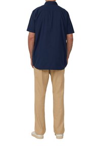 Marineblauw shirt met korte mouwen, kraag, rechte snit en een rugplooitje, gecombineerd met beige chinos en witte sneakers.