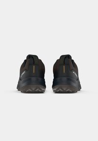 Scarpe da trail running per uomo con tomaia in marrone scuro e nero, tessuto testurizzato, tallone rinforzato e suola in gomma resistente con motivi di trazione.