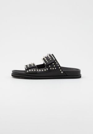 Black slide sandals featuring two wide straps adorned with silver studs and buckles, with a flat sole and smooth texture.
