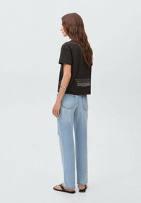 Camiseta de algodón negra con mangas cortas; jeans rectos de mezclilla azul claro con detalles desgastados; sandalias sencillas; diseño minimalista.