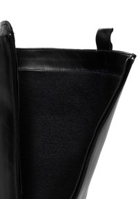 Bolso de mano de cuero negro con un exterior suave y cierre de cremallera, con un forro interno de tela negra suave visible.