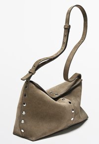 Schultertasche aus taupefarbenem Wildleder mit verstellbarem Riemen und silbernen Metallnieten entlang der Kanten und des Klappverschlusses.
