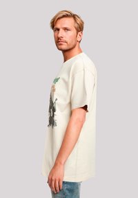 Beige cotton t-shirt with a relaxed fit, short sleeves, and a graphic print featuring text and a design on the front.