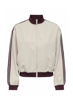 Beige jas met een hoge kraag, ritssluiting aan de voorkant en elastische zoom. Heeft wijnrode mouwstrepen en zijzakken. Soepele textuur.