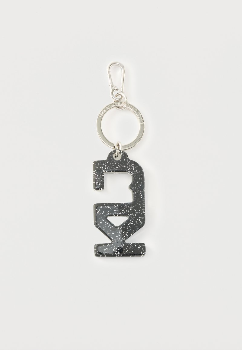 Brelok z czarnym brokatem z wyciętym wzorem, przymocowany do metalowego pierścienia i klipsa. Gładka faktura z metalicznym połyskiem.