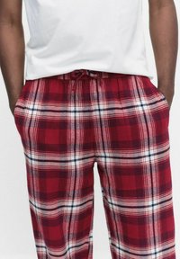 Rode geruite pyjamabroek met een trekkoord in de taille, met een zachte textuur en een patroon van witte en marineblauwe lijnen die over de stof kruisen.