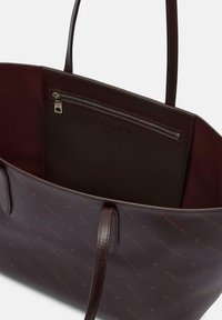 Burgundowa skórzana torba na ramię z dwoma rękawami, z zamkiem błyskawicznym wewnątrz i wytłaczanym wzorem logo "Berlin" na zewnątrz.