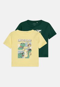 To bomull t-skjorter: en gul med et dinosaur-motiv, en mørkegrønn med et enkelt design. Korte ermer og rund hals.