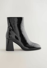 Czarne botki za kostkę z błyszczącym lakierowanym wykończeniem, kwadratowym noskiem i wyraźnym grubym obcasem, o gładkich, eleganckich kształtach i bez widocznych elementów metalowych.