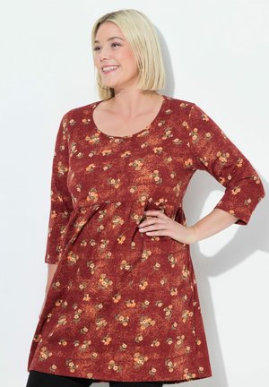 Robe de couleur rouille avec un petit motif floral, décolleté en scoop et manches trois-quarts. Tissu texturé avec des détails de taille froncée.