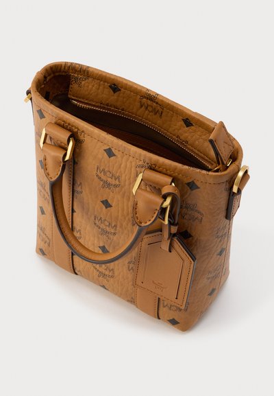 Sac à main en cuir marron texturé avec logo MCM embossé, double poignée, fermeture zip sécurisée et attache pour étiquette de bagage.