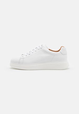 Baskets basses en cuir blanc avec un laçage à l'avant, col intérieur rembourré couleur tan, semelle texturée et embossage subtil de la marque sur le côté.