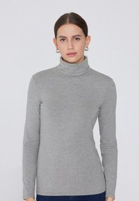 Maglione a collo alto grigio realizzato in tessuto morbido, con maniche lunghe e un design aderente, adatto per outfit casual o da sovrapporre.