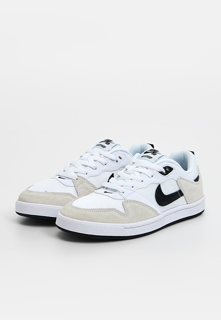 Weiße Sneaker aus Wildleder und Mesh-Materialien, mit einem schwarzen Nike-Swoosh, runder Zehenpartie und strukturiertem weißen Fußbett.