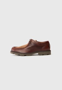Zapato de cuero marrón y ante con punta redondeada, costuras a tono y suela de goma con un patrón de tracción. Incluye detalles de cordones y un tabique trasero.
