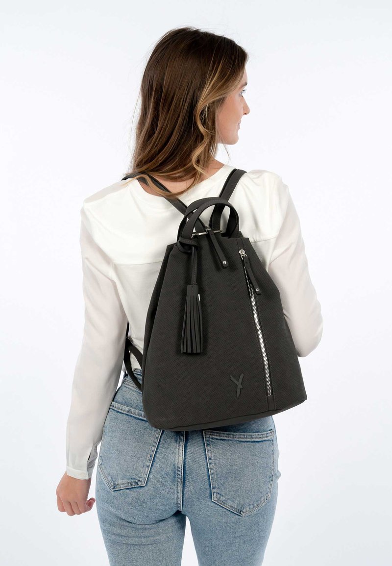 Black textured backpack with a drawstring closure, front zipper pocket, and a tassel accent. Adjustable straps and smooth fabric.