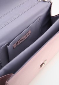 Roze synthetische handtas met een gladde textuur, voorzien van een grijze binnenkant, meerdere zakken en een verstelbare zilveren kettingriem.