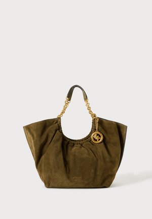 Sac fourre-tout en daim vert olive avec poignées chaîne dorée et pendentif rond avec le logo Michael Kors suspendu près de l'ouverture.