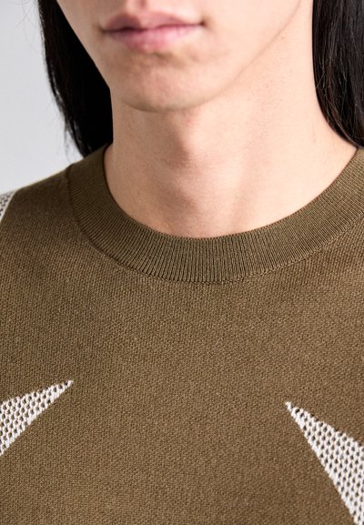 Barna kötött pulóver, bordázott kerek nyakkal és fehér csillagmintával. Zártkörű nézet, amely kiemeli a textúrát és a szövet részleteit.