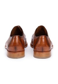 Chaussures en cuir marron à texture lisse, bout arrondi et petit talon en bois. Présentent des accents cousus le long des côtés.