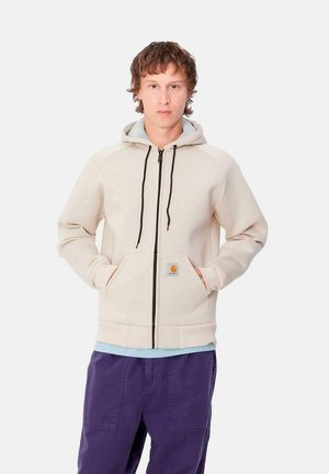 Sudadera con cremallera en un tono beige claro, con cremallera negra, bolsillos frontales y un forro interior azul en contraste. Mezcla de algodón con puños y dobladillo acanalados.